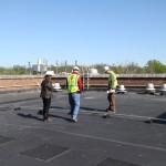 Three people look at the new roof section of Franklin Hall