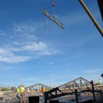 A crane lifts a steel beam onto the room of Franklin Hall