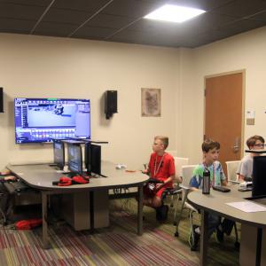 Three students and a camp staffer work in the game lab