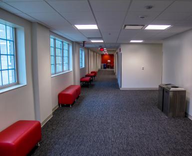 A renovated hallway on Ernie Pyle Hall’s second floor, with large windows, dark carpet, and bench seating under the windows