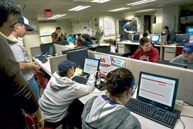 Students work on computers and discuss work in the Indiana Daily Student newsroom in Ernie Pyle Hall