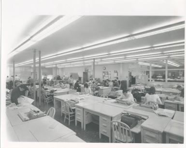 A black and white photo of rows of wooden desks with typewriters