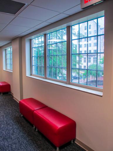 A window in the renovated Ernie Pyle Hall faces the Indiana Memorial Union. There are red backless cushioned seats in front of the window