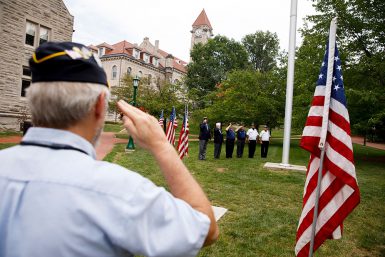 A veteran salutes as an honor guard raises a flag outside of Franklin Hall.