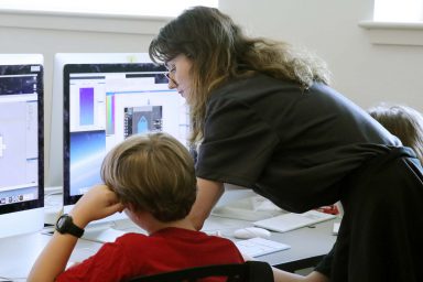 Camp counselor Melanie Goldstone, a student at the Indiana Academy for Science, Mathematics, and Humanities, helps Cosmo Pearson-Young, a sixth-grader at Templeton Elementary in Bloomington, in the 2D game development camp.