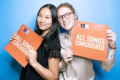 Emily Abshire and another NPR intern post with orange posters that read 