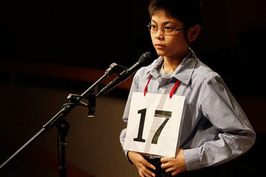 A contestant of the spelling bee stands at a microphone
