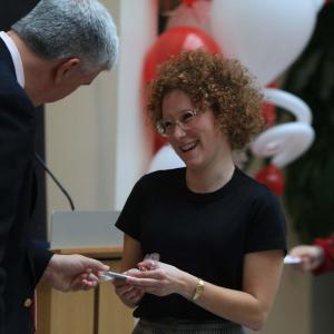 Dean Jim Shanahan recognizes a smiling Emily Abshire with a handshake and a small gift.