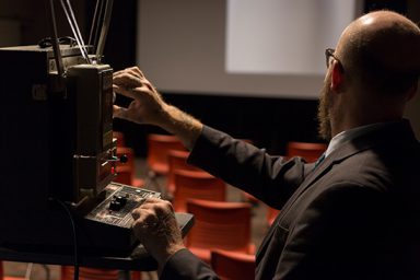 Andy Uhrich, film archivist and assistant librarian at the Indiana University Libraries Moving Image Archive, sets up a projector in the screening room (Wells Library 048) where students can come to screen films at high quality.