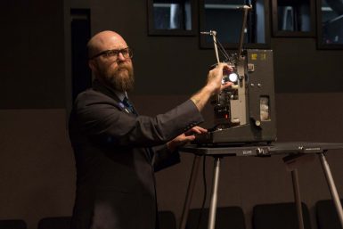 Andy Uhrich, film archivist and assistant librarian at the Indiana University Libraries Moving Image Archive, sets up a projector in the screening room (Wells Library 048) where students can come to screen films at high quality.