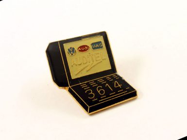 A Minitel lapel pin with the number 3614 printed on the bottom half.