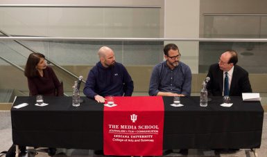 A group of four people sit at a black table.