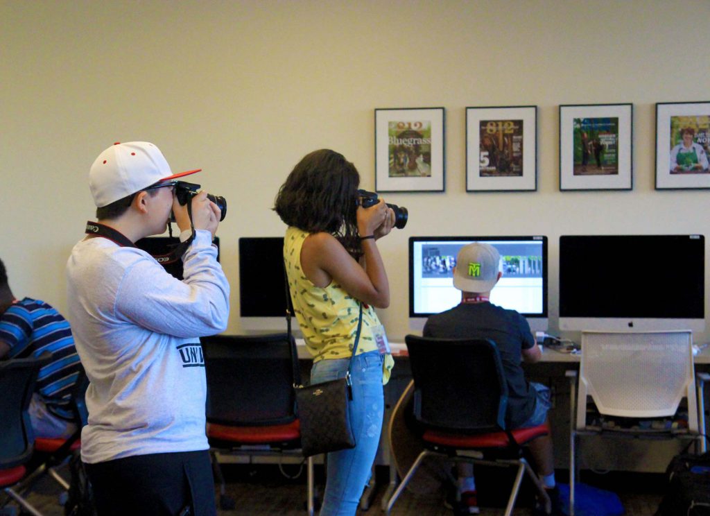 Students in a photojournalism class take photos of the different workshops.