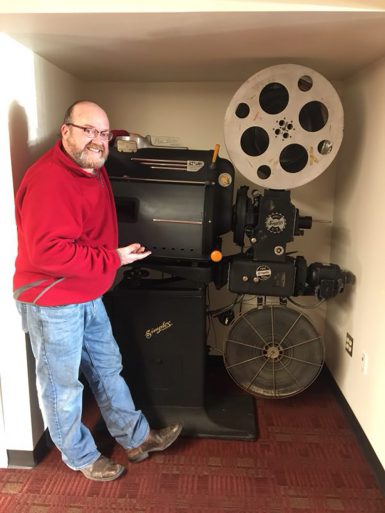 Man standing in front of a large film projector
