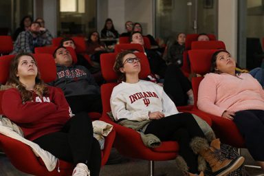 Students look up toward the large screen in The Media School's commons