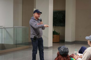 Michael Uslan standing, speaking into a microphone.