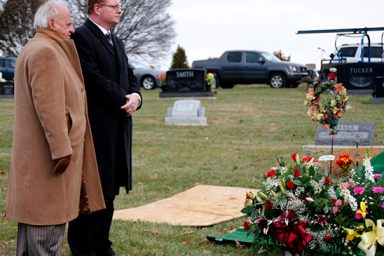 Two men standing next to a gravesite