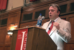 Journalist Christopher Hitchens speaking at a podium