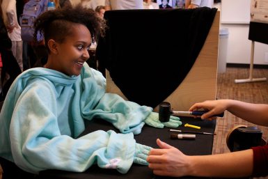 A young girl participates in a psychological experiment that addresses touch and sight sensations utilizing a fake hand.