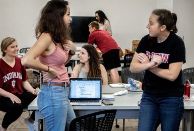 Students talk in a classroom.