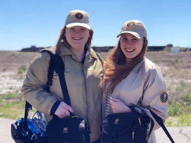 Students Sydney Ziegler and Anna Howell wear volunteer uniforms during the 2018 Gulf Islands National Seashore alternative spring break trip. Students wore the uniforms so visitors would be more comfortable with student reporters approaching them.