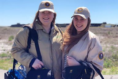 Students Sydney Ziegler and Anna Howell wear volunteer uniforms during the 2018 Gulf Islands National Seashore alternative spring break trip. Students wore the uniforms so visitors would be more comfortable with student reporters approaching them.