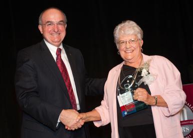 Blewett accepts the IU School of Journalism's inaugural Distinguished Alumni Award from IU president Michael McRobbie.