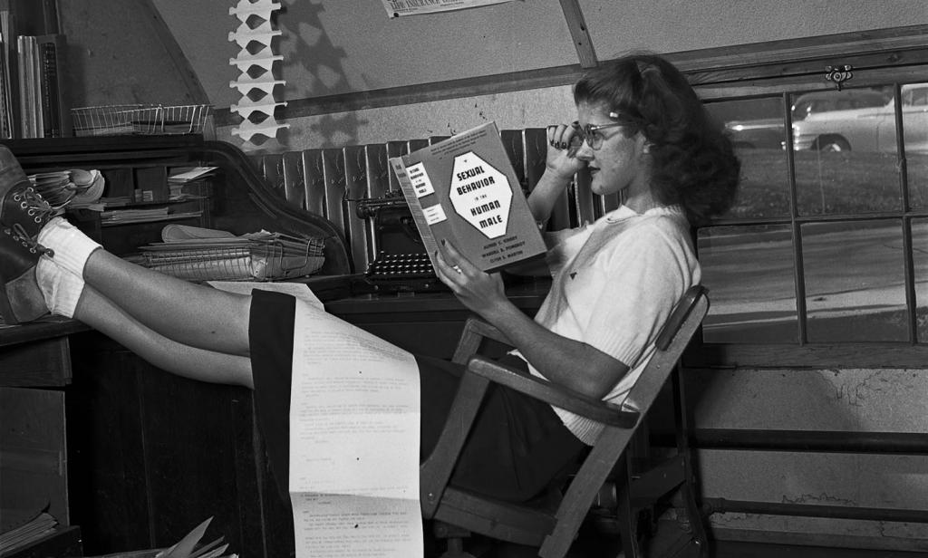 Marjorie (Smith) Blewett reads Alfred Kinsey's "Sexual Behavior in the Human Male" at the Indiana Daily Student editor's desk.