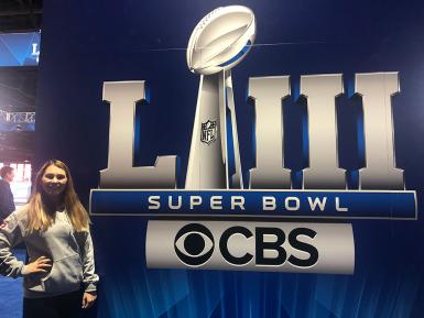 Morgan Gard stands in front of a sign that says "LIII Super Bowl CBS"