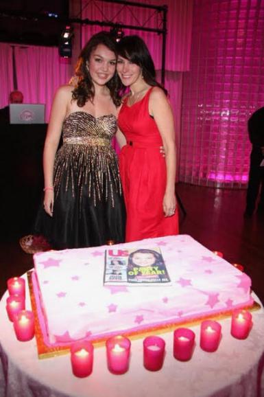 Peri Sedge and Lori Levine pose behind a cake with an image of a People magazine cover.