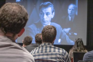 The audience watches a clip from the 1936 film, "Mr. Deeds Goes to Town." 