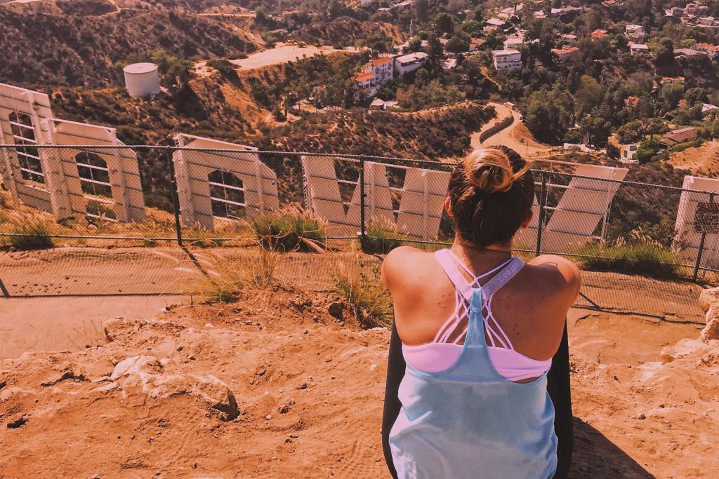 A woman sits atop Mount Hollywood and looks down at the city.