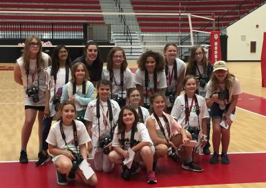 Fourteen girl scouts pose with volleyball player Kamryn Malloy on the court.