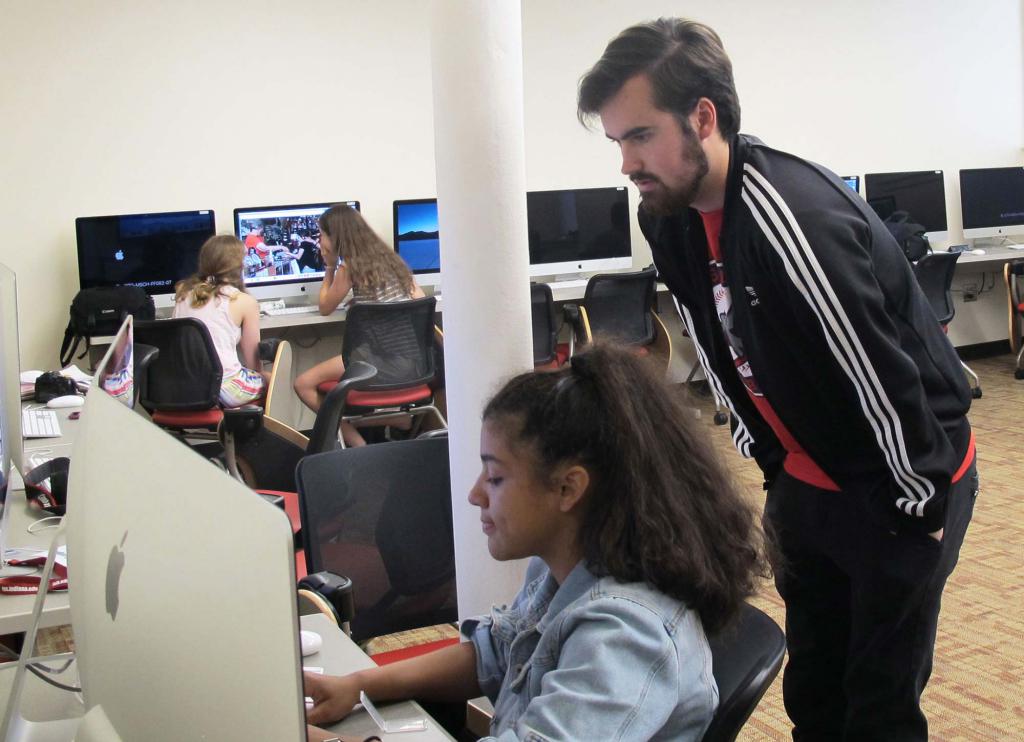 Sam House looks over a student's shoulder as she works on a computer.