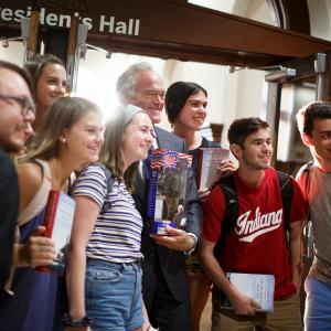 Scott Pelley poses for a photo with students. He's holding an Ernie Pyle G.I. Joe doll.