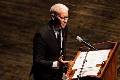 Anderson Cooper speaking at a podium into a microphone