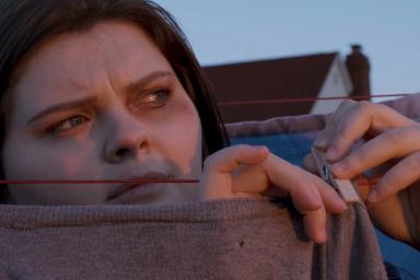 A woman hangs a sweater on a clothesline