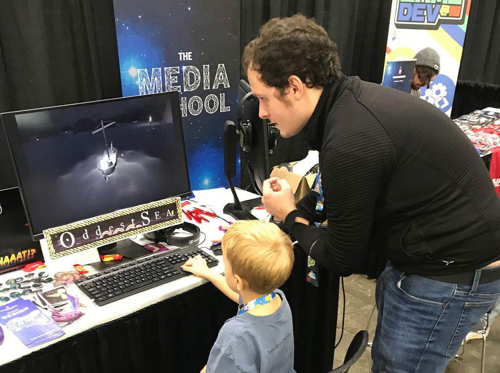 Matt Olry shows a child how to play his video game, "Oddest Sea"