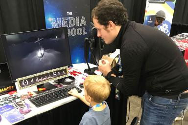 Matt Olry shows a child how to play his video game, 