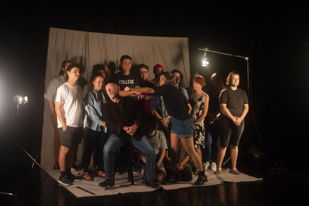 Jonathan Banks poses in a studio with 14 students. Alyssa Woolard pretends to punch him in the face.