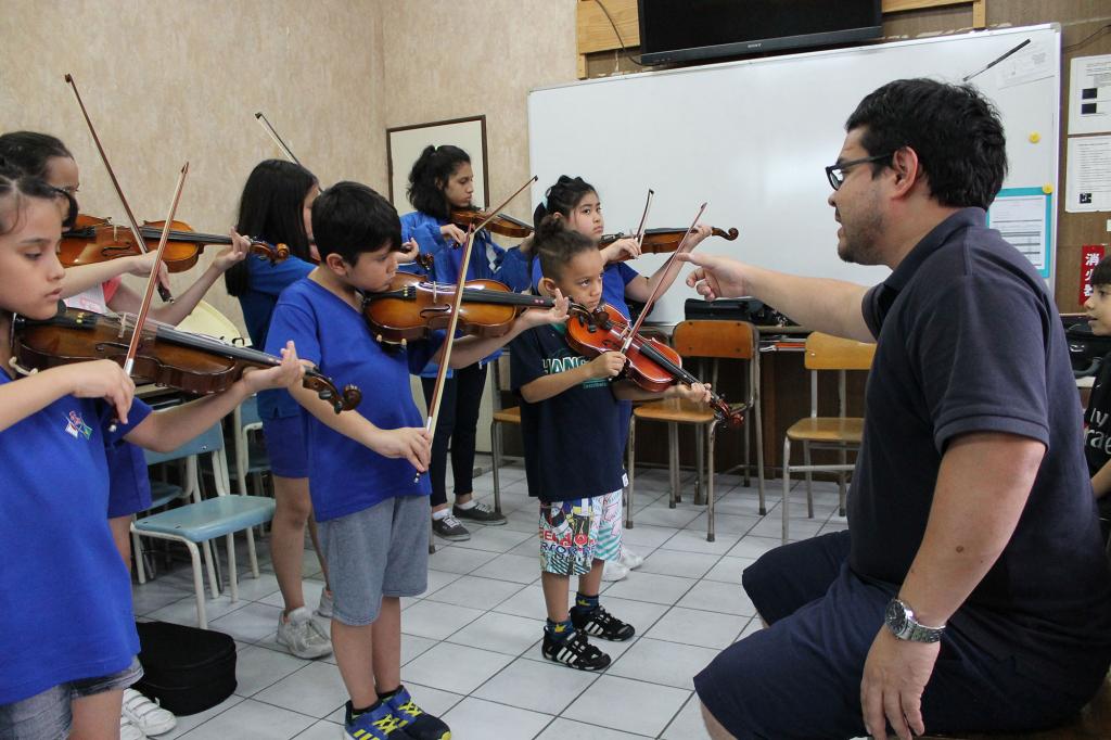 Rafael Kinoshita conducts an orchestra of child violinists