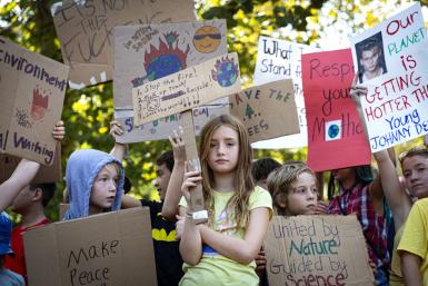 Children hold protest signs during the Bloomington Climate Strike.