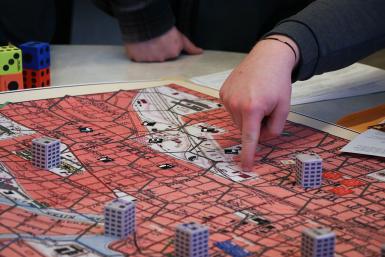 Closeup of the game board, which looks like a city, and someone pointing at it