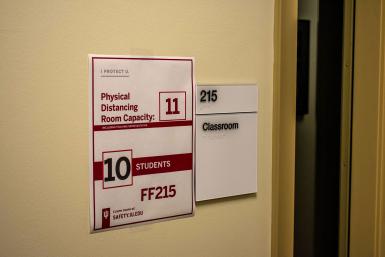 A sign says "Physica Distancing Room Capacity. 11. 10 students. FF215"