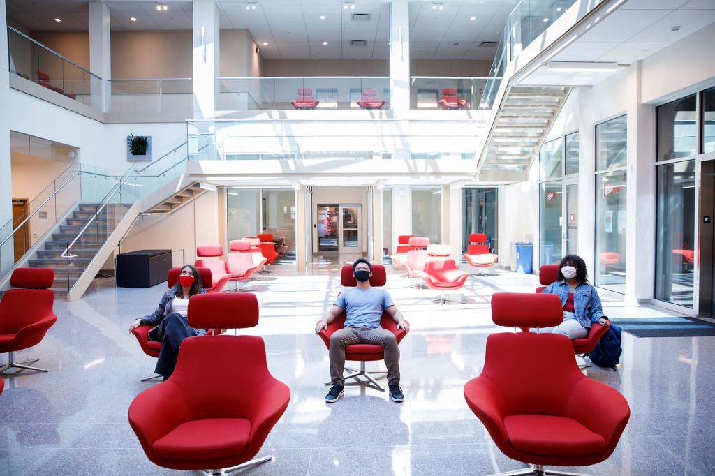 Three students sit in chairs in the Franklin Hall commons