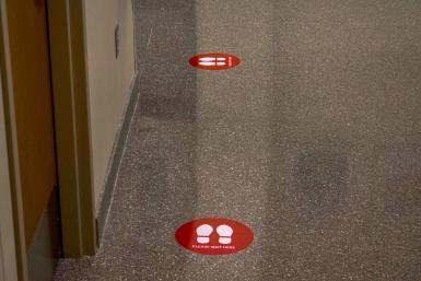 A floor with two stickers that say "Please Wait Here"