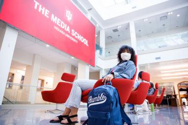 A student sits in the commons wearing a mask