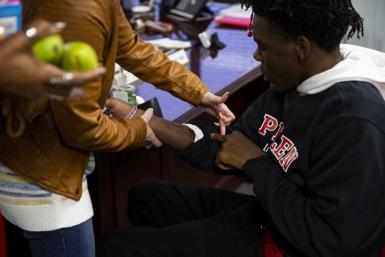 Nicole Fama, principal of James and Rosemary Phalen Leadership Academy, looks at one of Da’Quincy Pittman’s scars on the forearm doctors sliced open to dig out a bullet.