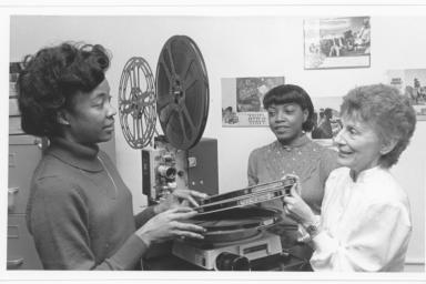 Three women looking at reels of film