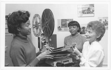 Three women looking at reels of film